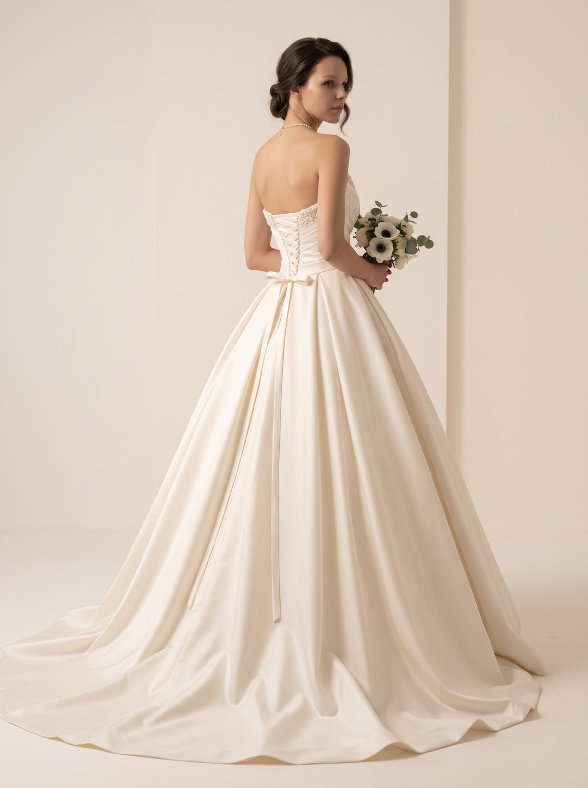 Kaelia structured satin A-line wedding dress back view featuring an intricate lace-up corset back and chapel train by Fiore's Bridal - Back View