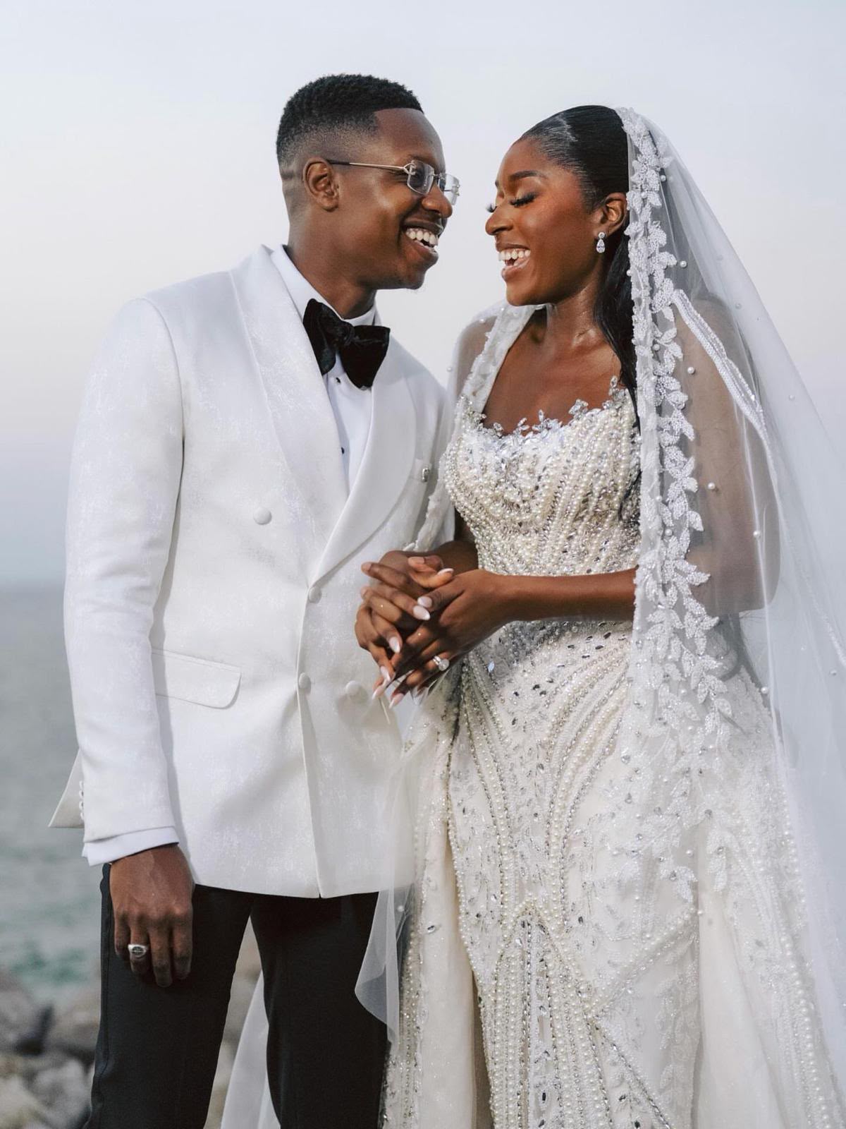 Kady and Samo laughing together on their wedding day, Kady in a pearl and crystal embroidered Fiore's Bridal gown